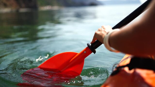 Kayak paddle sea vacation. Person paddles with orange paddle oar on kayak in sea. Leisure active lifestyle recreation activity rest tourism travel