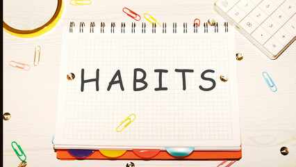 HABITS word on a checkered notebook on a light table next to a magnifying glass