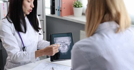 Female doctor and patient at reception are discussing an x-ray of sinuses. ENT and deviated septum