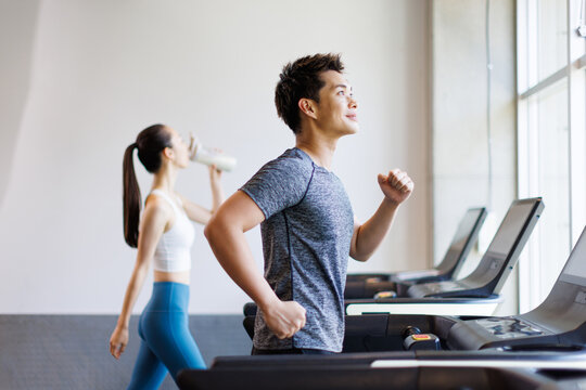 トレッドミルで走っている若いアジアの大人