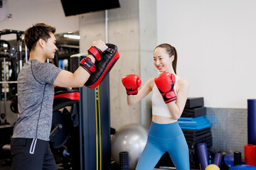 アジアの若い女性はパーソナルトレーナーとボクシングを練習します