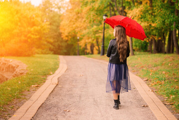 Young attractive smiling girl under umbrella in autumn forest