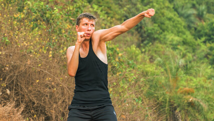 young man boxing against the backdrop of a forest