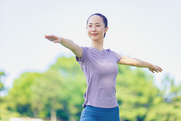 公園でヨガを練習する若いアジア人女性