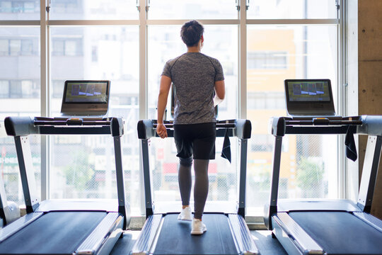 トレッドミルを歩いている若いアジア人