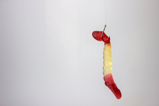 Fishing lure with a red and yellow worm on a white background