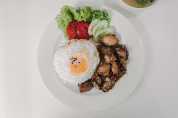 Rice with Basil Fried Chicken and fried egg served on white dish.