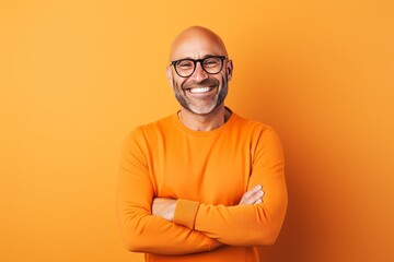 Portrait of happy mature man in orange sweater and eyeglasses on orange background