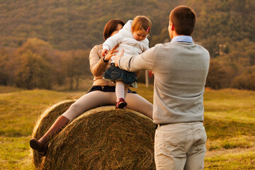 Underneath the verdant mountains, a family revels in nature. The daughter finds joy on a hay bale,...