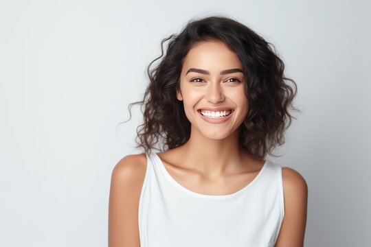 Closeup photo portrait of a beautiful young latin hispanic model woman smiling with clean teeth. Used for a dental ad. Isolated on light background.