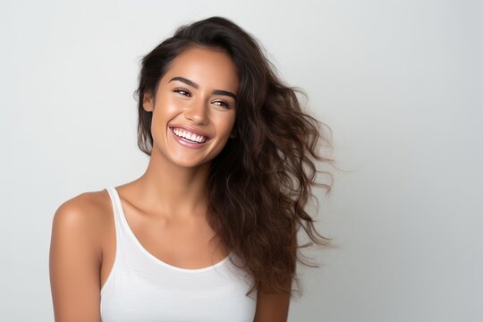 Closeup photo portrait of a beautiful young latin hispanic model woman smiling with clean teeth. Used for a dental ad. Isolated on light background.