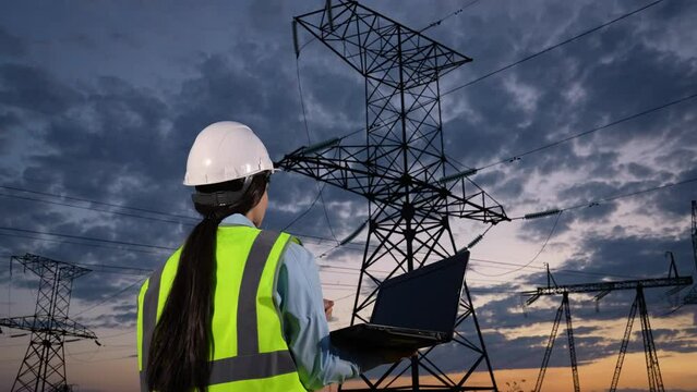 Engineer controls information on laptop walking to power transmission lines