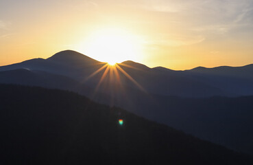 dark silhouettes of the Carpathian mountains in the first rays of the rising sun, closed aperture