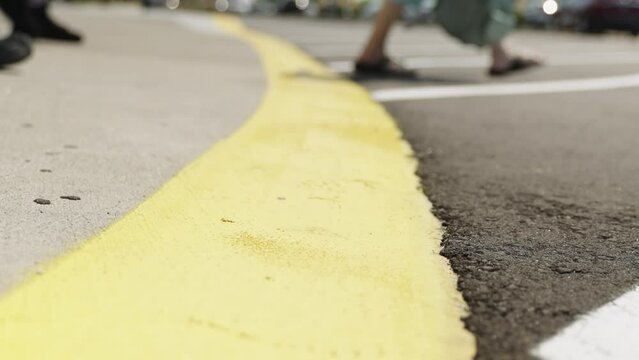 People crossing yellow line at parking lot, low angle closeup