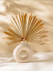 Ceramic vase with palm leaf on the table and sunlight shadows, scandinavian cozy interior design....