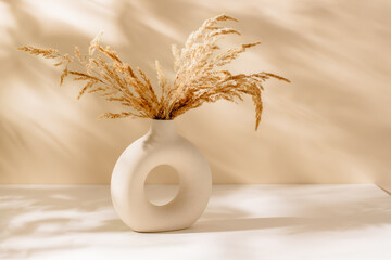 Modern ceramic vase with pampas grass on the table and sunlight shadows, scandinavian interior...