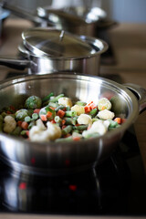 Cooking ratatouille in a metal pan. Frozen vegetable mix for dinner. Vegetarian Lunch Mix