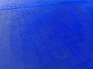 blue plastic tiles with a perforated surface serve as a flat surface for organizing outdoor dance...