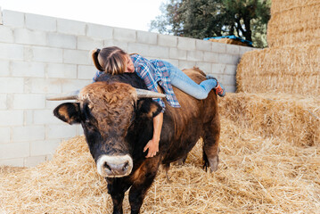 Relaxed attractive female farmer lying on bull in haystack barn