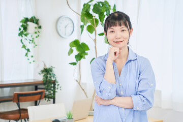 顎に手を当てる自宅で仕事をする女性　立ちポーズ