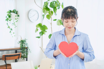 ハートマークをもつ自宅で仕事をする女性　立ちポーズ