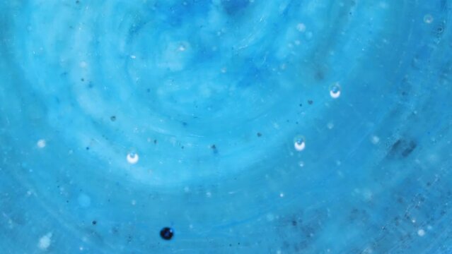 Abstract art background of swirling silver, blue and black colors, ink bubbles burst and react