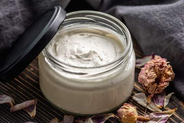 Natural fragrant cream or butter for body in a clear glass jar on a wooden background. Concept of...