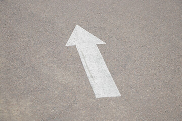 Fototapeta premium A white arrow pointing forward is drawn on the asphalt on the road as a background, the way forward
