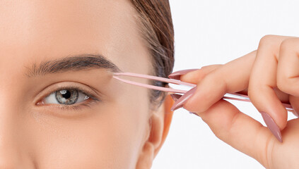 Young attractive woman in a white coat plucking eyebrows. Professional make-up and cosmetic skin...