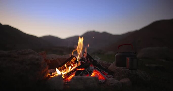 Campfire flame at dusk. Slow motion. Halt for night in mountains in wild deserted area. Beautiful cinematic bonfire flame. Love for nature, hiking in a friendly company, family hiking. 