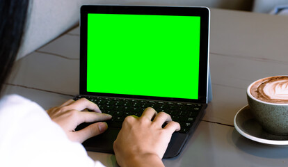Close up of freelencer using laptop computer with mock up green screen chroma key display in cafe.