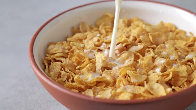 Milk is poured into a bowl of organic corn flake.