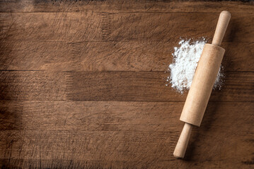 Rolling pin and flour on wooden board