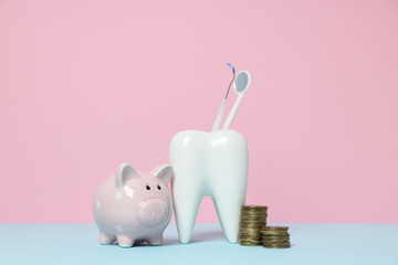 Piggy bank, decorative tooth and coins on pink background