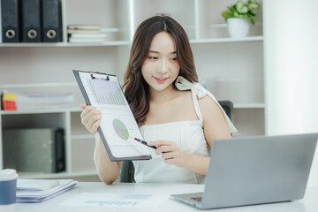 Young independent Asian woman working on laptop computer in modern office Perform accounting analysis, report real estate investment data. Financial concepts and tax system