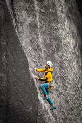 Fotobehang Person climbing in high mountains with yellow jacket rope and helmet in nature, confidence and risk, safety © VICTOR