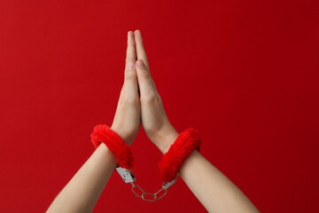 Red, fluffy handcuffs for sex play on a red background.