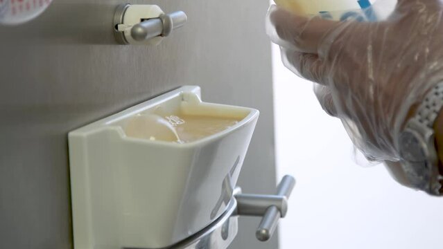 Pouring creamy gelato base into spout for gelato batch freezer machine