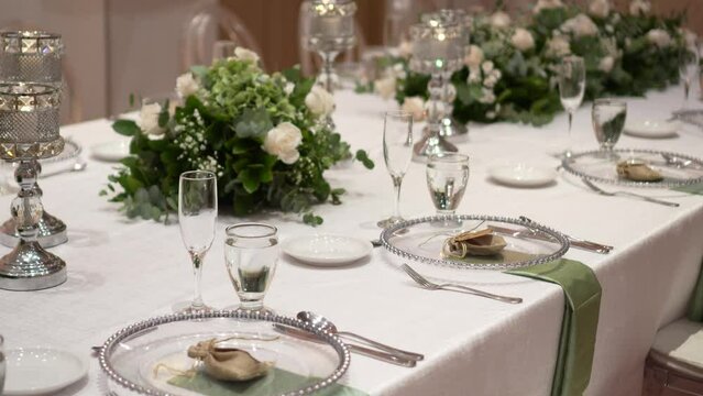 Wedding table setting decorated with fresh flowers. Wedding floristry. Banquet table for guests. Bouquet with roses, eustoma and eucalyptus leaves