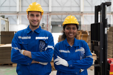 Male and female engineer worker wearing safety uniform and helmet standing with crossed arms in...