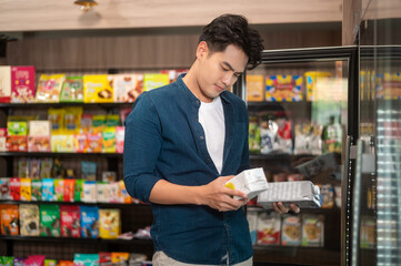 A young asian man shopping in supermarket , concept of city life lifestyle