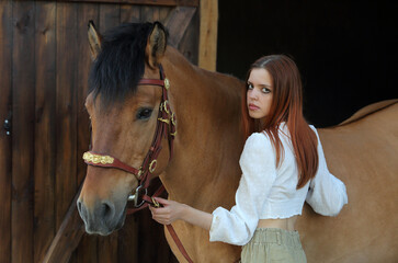 Beautiful country girl posing with  horse in the ranch