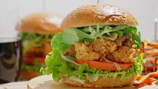Crispy, breaded chicken double burgers with vegetables and drink, served with sweet potatoes