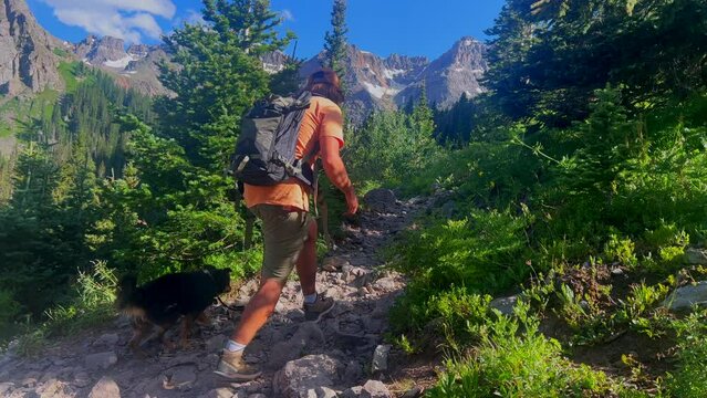 Cinematic aerial people hiking with dog alpine Blue Lakes walk Colorado Mount Sniffels Dallas Peaks Wilderness snow 14er peak purple wildflowers Ridgway Telluride Ouray Silverton slow follow still
