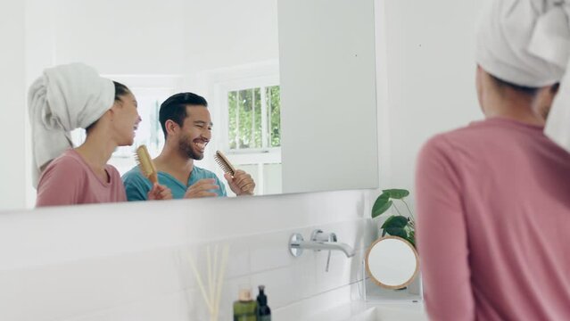 Brush, singing and young couple in the bathroom doing a self care, clean and shower routine. Morning, karaoke and happy man and woman dancing, bonding and having fun for body treatment in modern home