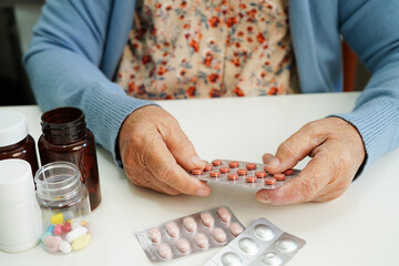 Asian elderly woman holding pill drug in hand, strong healthy medical concept.