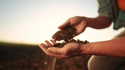 soil in the hands of the farmer. agriculture. close-up of a farmers hands holding sun black soil in...