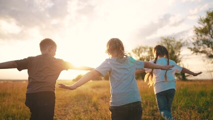 kids run in the park at sunset. happy family children camp kid dream concept. a group of children run on the grass at sunset the rays of the sun silhouette. childhood dream fun teamwork concept