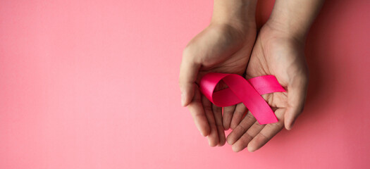 pink ribbon placed on the hand sick person suffering from cancer, world cancer day, healthcare and medicine backdrop, suicide prevention, children health care.