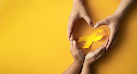 yellow ribbon in hands sick person suffering from cancer make heart symbol, world cancer day,...